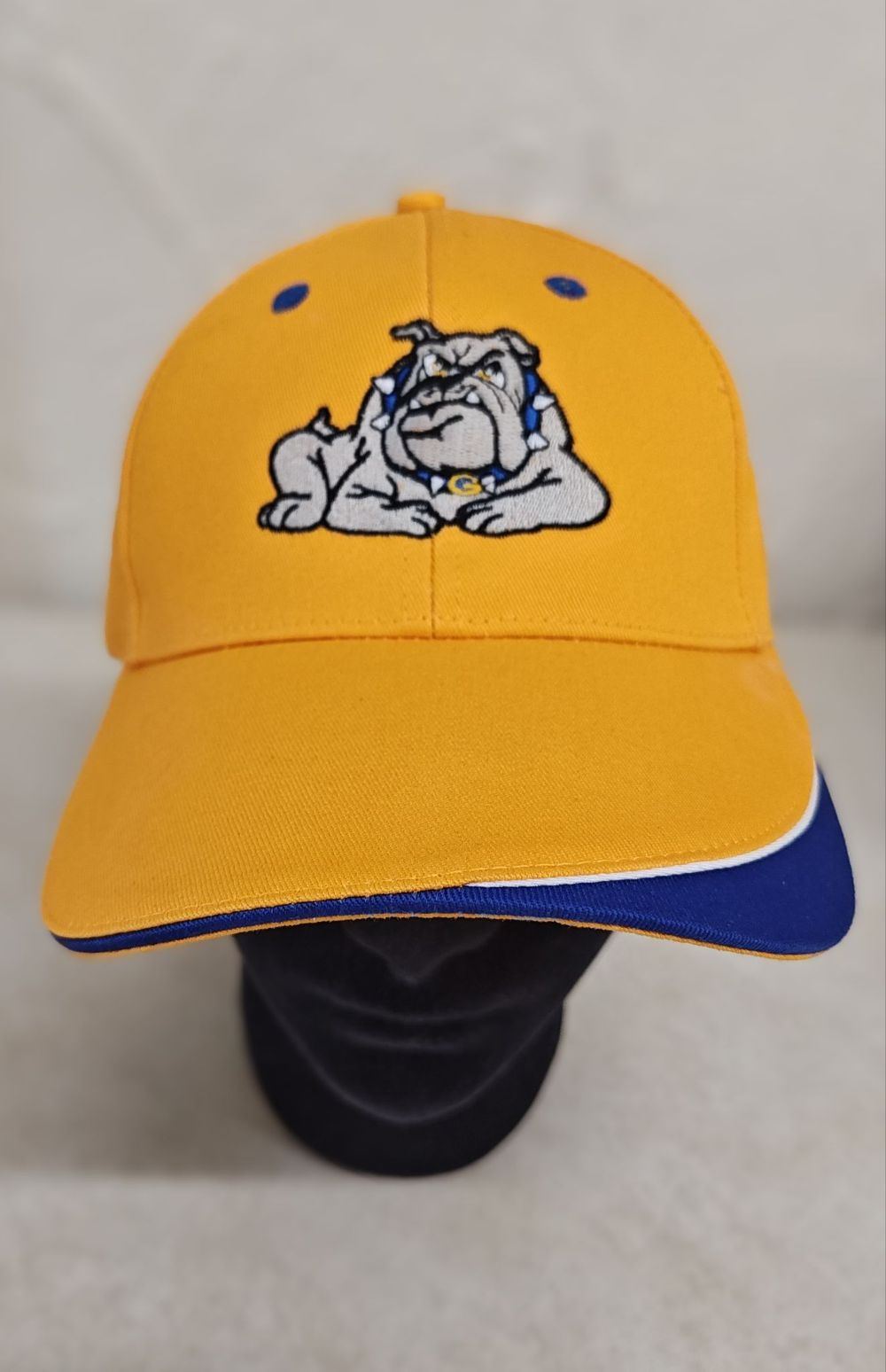 Yellow baseball cap with a detailed embroidered bulldog mascot wearing a blue spiked collar